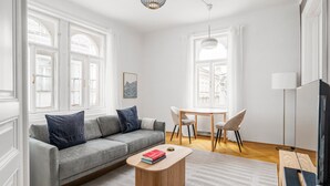 A modern living room with a grey sofa, a round coffee table, a dining table with chairs, and a television. - Blueground | Neubau, view, nr MuseumsQuartier (Vienna)