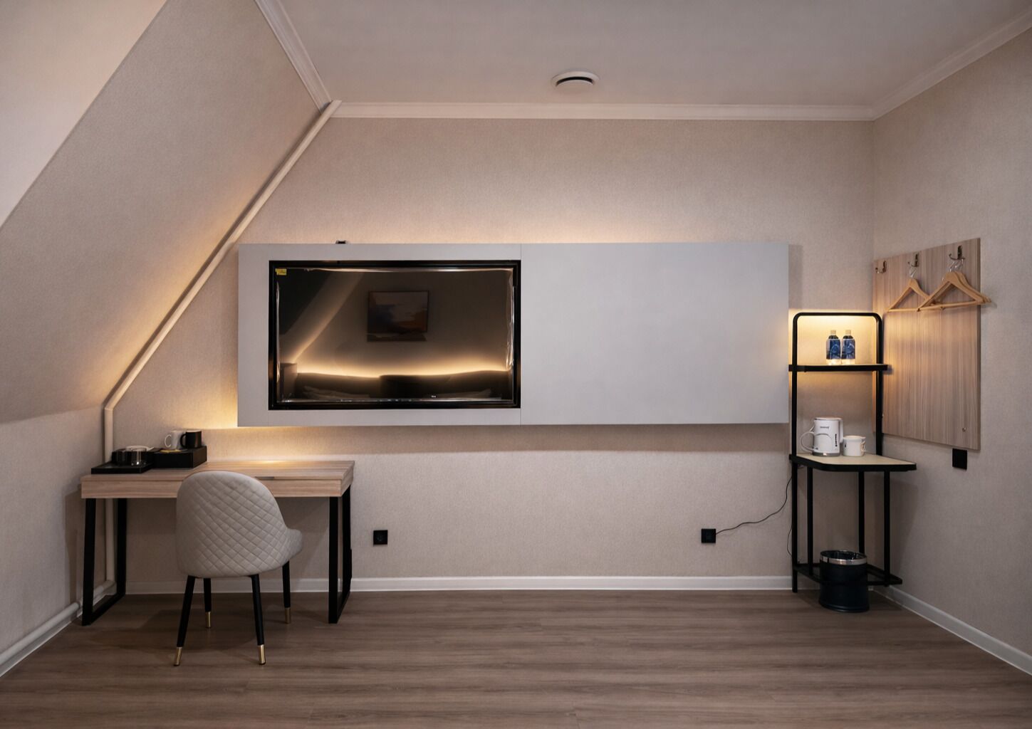 A modern, minimalist room with a desk, chair, and a mounted TV.