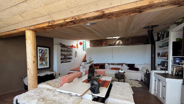 A cozy living room with a sofa, a coffee table, and a fireplace. There is a bookshelf and a painting on the wall.