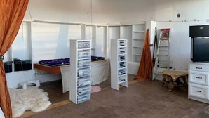 A room with a bed, storage units, a TV, and a ladder.