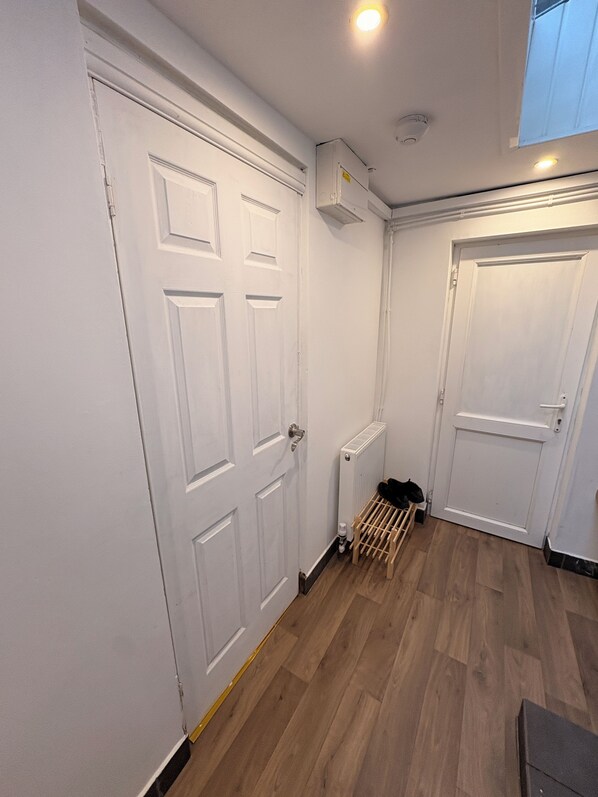 A hallway with white doors, a radiator, and a wooden rack. - Cosy living space in Birmingham (Birmingham)
