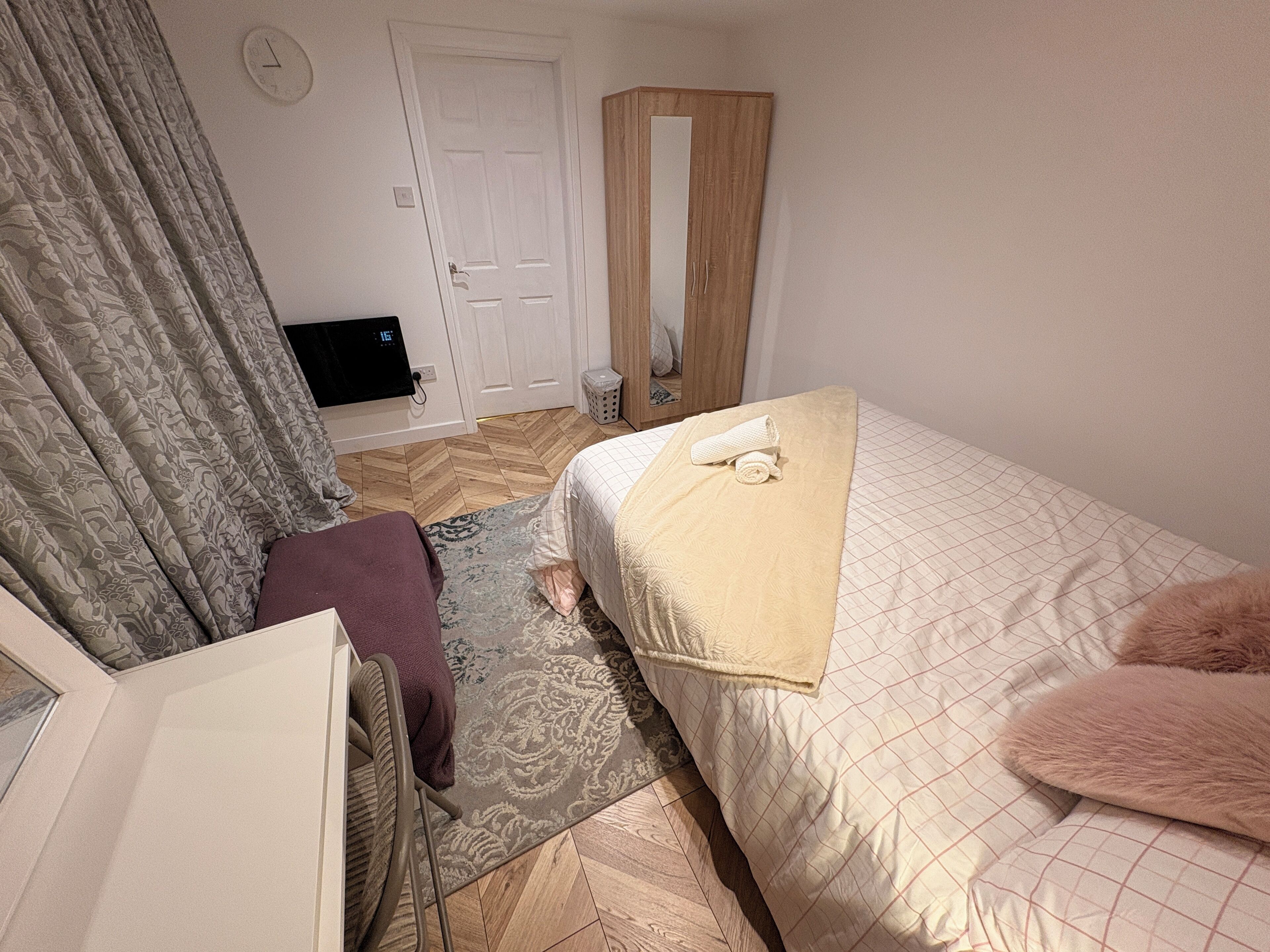 A bedroom with a bed, a chair, a mirror, a door, and a television.