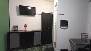 A small room with a TV mounted on the wall, a cabinet with a mirror, a small table with a chair, and a door with a sign. - ROOM FOR TWO PEOPLE CLOSE TO OAXACA CITY (Santa Cruz Xoxocotlán)