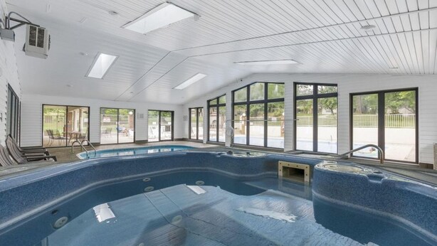 Ein Innenpool mit großen Glaswänden, einer Decke mit Einbuchtungslichtern und Blick ins Freie.