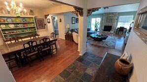 A dining area with a wooden table and chairs, a green shelf with decorative items, and a kitchen area with a refrigerator and stove. - Charming 3-bedroom house 20 min. To downtown Austin, 20 min. To Dripping Springs (Austin)