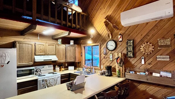 A rustic kitchen with wooden cabinets, a long counter, and a clock on the wall. - Cozy Cabin in the Woods, Anatone, WA (Anatone)