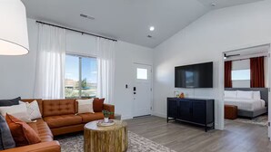A modern living room with a sofa, a round wooden coffee table, and a flat-screen TV mounted on the wall. - Kanab Retreat | Hot Tub, EV Charger, Near Zion (Kanab)