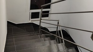 Una scala con ringhiera in metallo, una finestra con un telo oscurante e due lampade a sospensione.