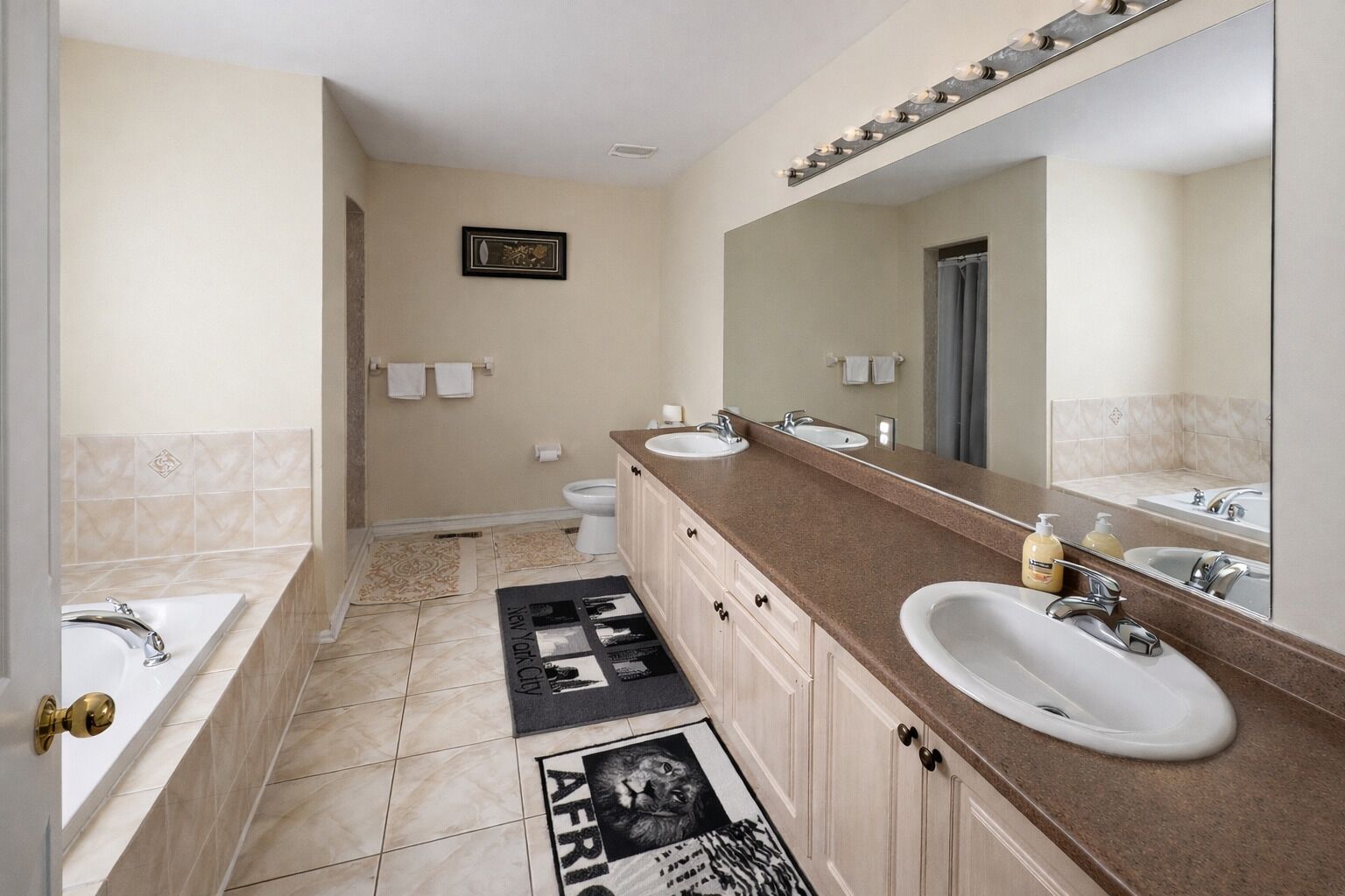 A modern bathroom with a double sink vanity, a large mirror, and a shower area.