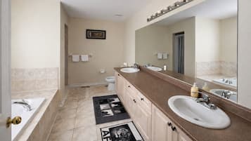 A modern bathroom with a double sink vanity, a large mirror, and a shower area.
