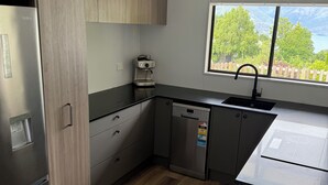 Ett modernt kök med inbyggd diskmaskin, kaffemaskin och ett fönster med utsikt över grönområden.