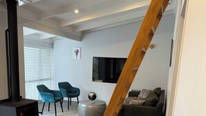 Ett modernt vardagsrum med en trätrappa, en öppen spis, en tv och en soffa.
