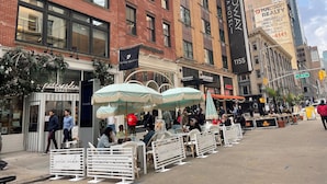 A street with outdoor seating, a hotel named 'Broadway Plaza Hotel,' and a building with 'Hadson Realty' signage. - Nest Aparthotel Manhattan  (New York)