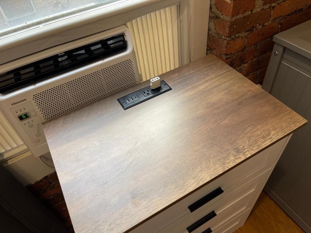 A kitchen with a wooden countertop, a Hisense appliance, and a brick wall.