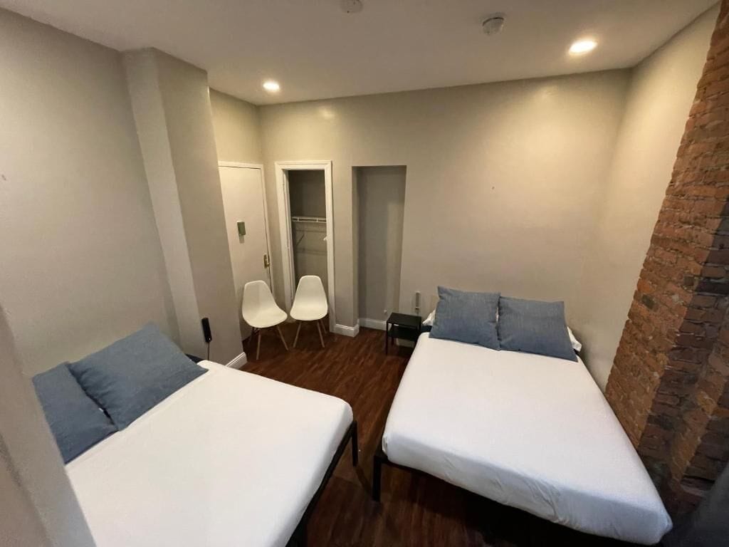 A room with two beds, a brick wall, and a door leading to a closet.