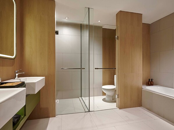 A modern bathroom with a glass shower enclosure, a toilet, a sink, and a bathtub. - ARTOTEL Living World Grand Wisata Bekasi (Bekasi)