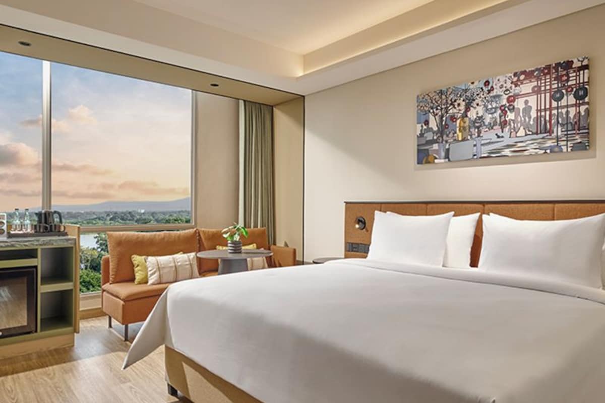 Una habitación de hotel moderna con una cama grande, un escritorio y vistas a la ciudad.