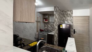 Eine kleine Küche mit Kühlschrank, Waschmaschine und Spüle.