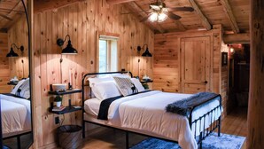 A cozy wooden cabin bedroom with a bed, bedside tables, and a ceiling fan. - Secluded Cabin near Lake Vermillion, Sleeps 10, with Hot Tub, and Pet Friendly (Angora)