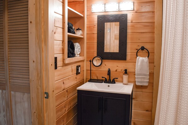 Un baño rústico con cabaña, que incluye un lavabo, espejo y toallero.