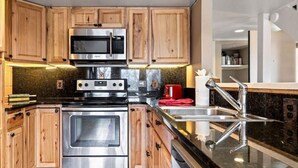 Una cucina moderna con mobili in legno, elettrodomestici in acciaio inossidabile e un piano di lavoro in granito.