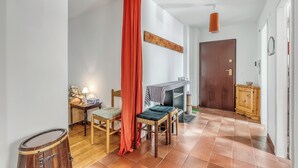 Een kamer met een houten deur, een kleine tafel met een lamp, een stoel en een rood gordijn.