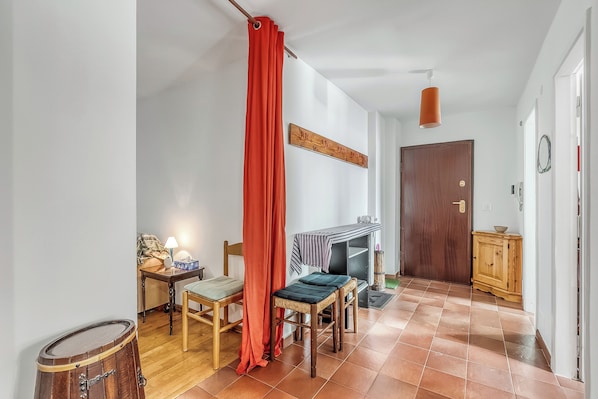 A room with a wooden door, a small table with a lamp, a chair, and a red curtain. - Gran Roc 23 with Parking near Slopes, Sestriere, Italy (Sestriere)