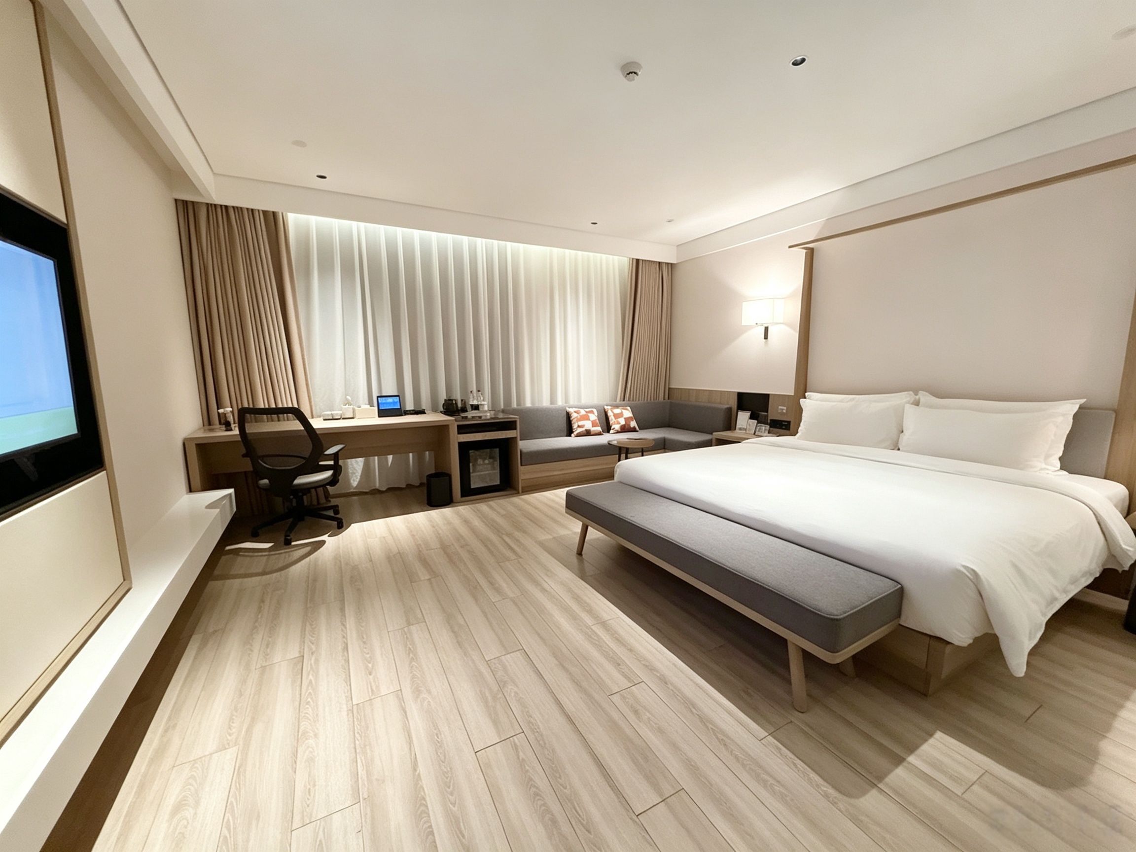 Una habitación de hotel moderna con una cama grande, un escritorio, una silla, un sofá y un televisor.