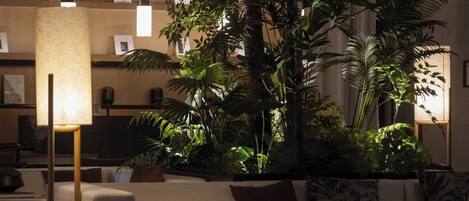 Eine moderne Lobby mit einer großen Pflanze in einem Topf, einer Couch und einer Stehlampe.