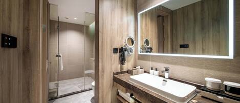 A modern bathroom with a large mirror, wooden paneling, a shower area, and a marble countertop.