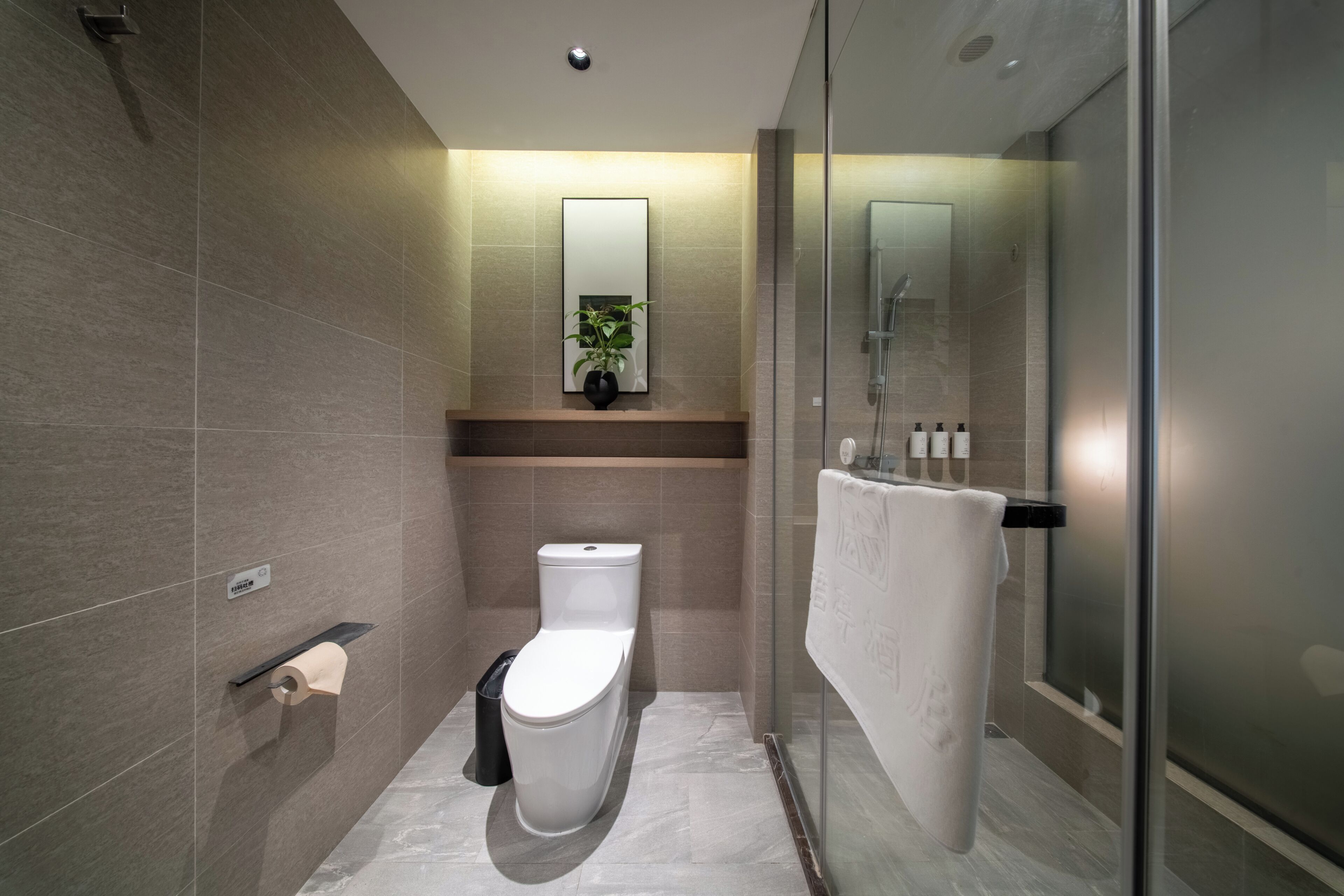 Une salle de bain moderne équipée de toilettes, d’un lavabo et d’une douche à parois de verre.
