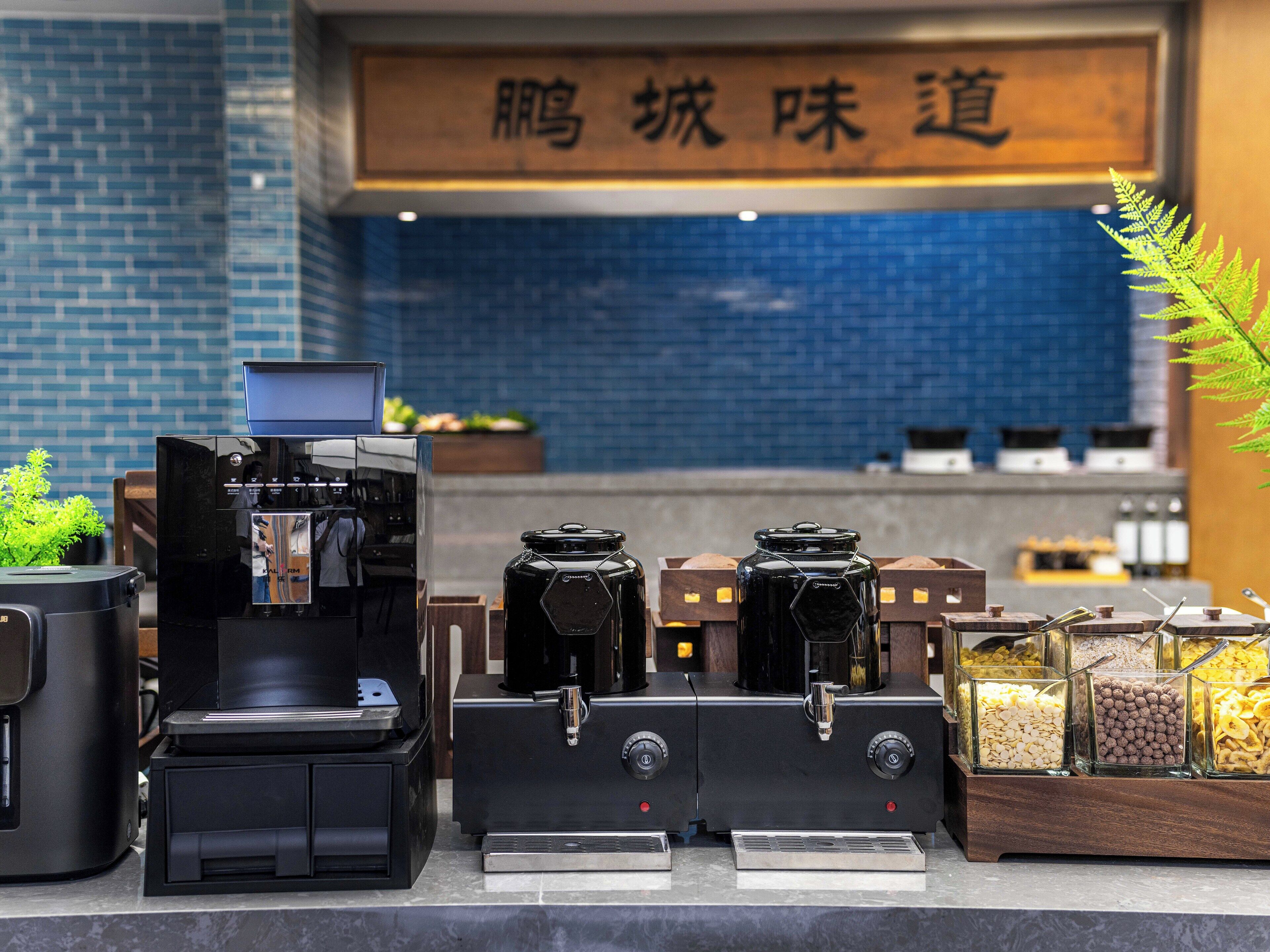 Una máquina de café y un molinillo sobre una encimera, con un cartel al fondo.