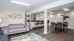 Una sala de estar moderna con un sofá gris, una mesa de centro y una zona de bar con taburetes.