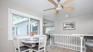 A dining area with a table and chairs, a ceiling fan, a window with a view, and a railing. - Fury House • Fenton/St Louis/Lindbergh • 4BR/3BA (Fenton)