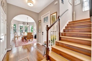 A staircase with wooden steps and a metal handrail, leading to a dining area with a table and chairs. - 3 Story Waterfront Home & Elevator w/ Hot Tub (Terra Ceia)