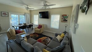 Ein Wohnzimmer mit grauem Sofa, einem Esstisch und Deckenventilatoren.