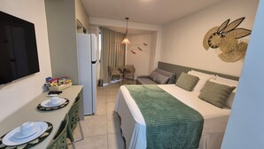 A hotel room with a bed, a desk with a chair, a television, and a wall decoration. - Carneiros Beach - Studio Max Carneiros - NEW (Tamandaré)