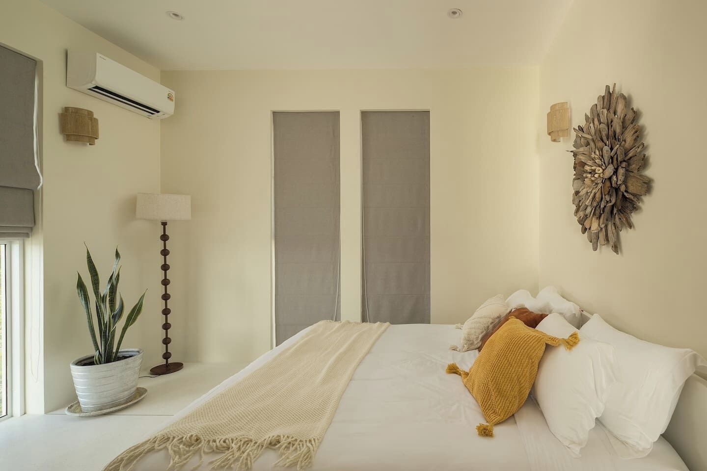 A bedroom with a bed, a potted plant, a lamp, and a wall decoration.
