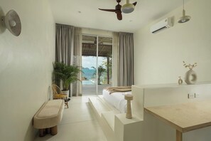 A modern hotel room with a bed, a small seating area, a wooden table, and a large window offering a view of the sea. - Rare 5BR Oasis - 30m to Sea
Lonely Beach Luxury Villas (Ko Pha-ngan)