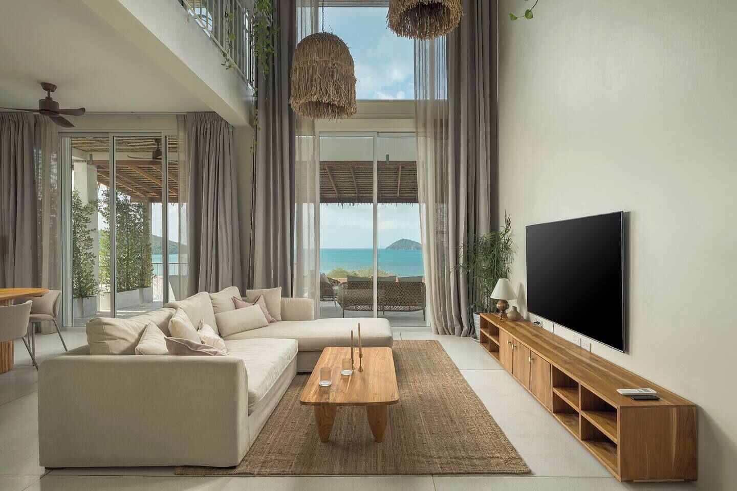 Una sala de estar moderna con sofá, mesa de centro, televisión y vista al mar.