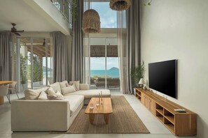 A modern living room with a sofa, coffee table, TV, and a view of the sea. - Rare 5BR Oasis - 30m to Sea
Lonely Beach Luxury Villas (Ko Pha-ngan)
