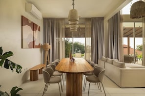 A modern living room with a wooden dining table, comfortable seating, and large windows offering a view of the outdoors. - Rare 5BR Oasis - 30m to Sea
Lonely Beach Luxury Villas (Ko Pha-ngan)