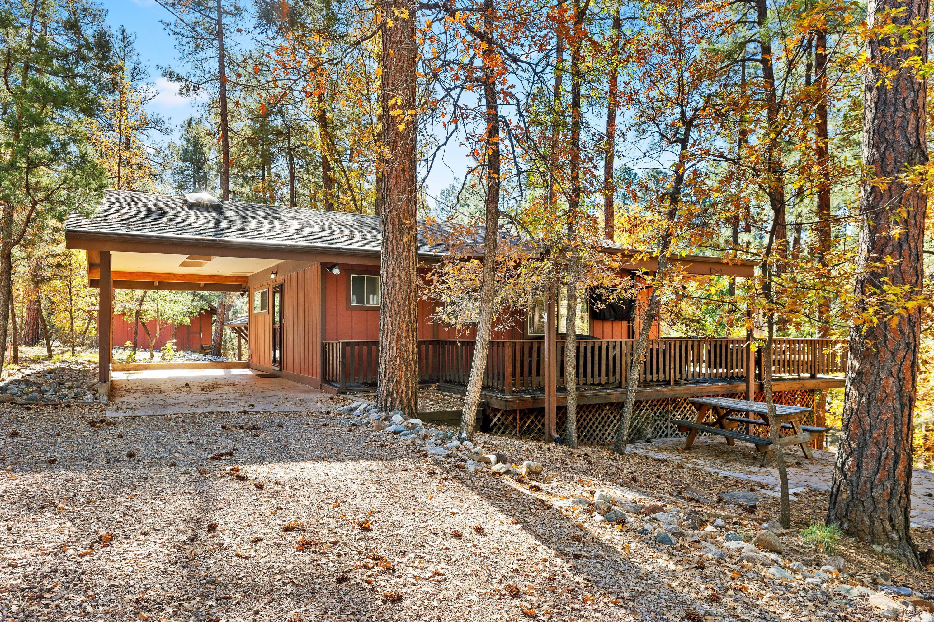 A cabin with a covered patio, a deck, and a picnic table.