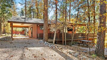 A cabin with a covered patio, a deck, and a picnic table.