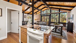 A modern kitchen with a large island, wooden beams, and a view of the outdoors.