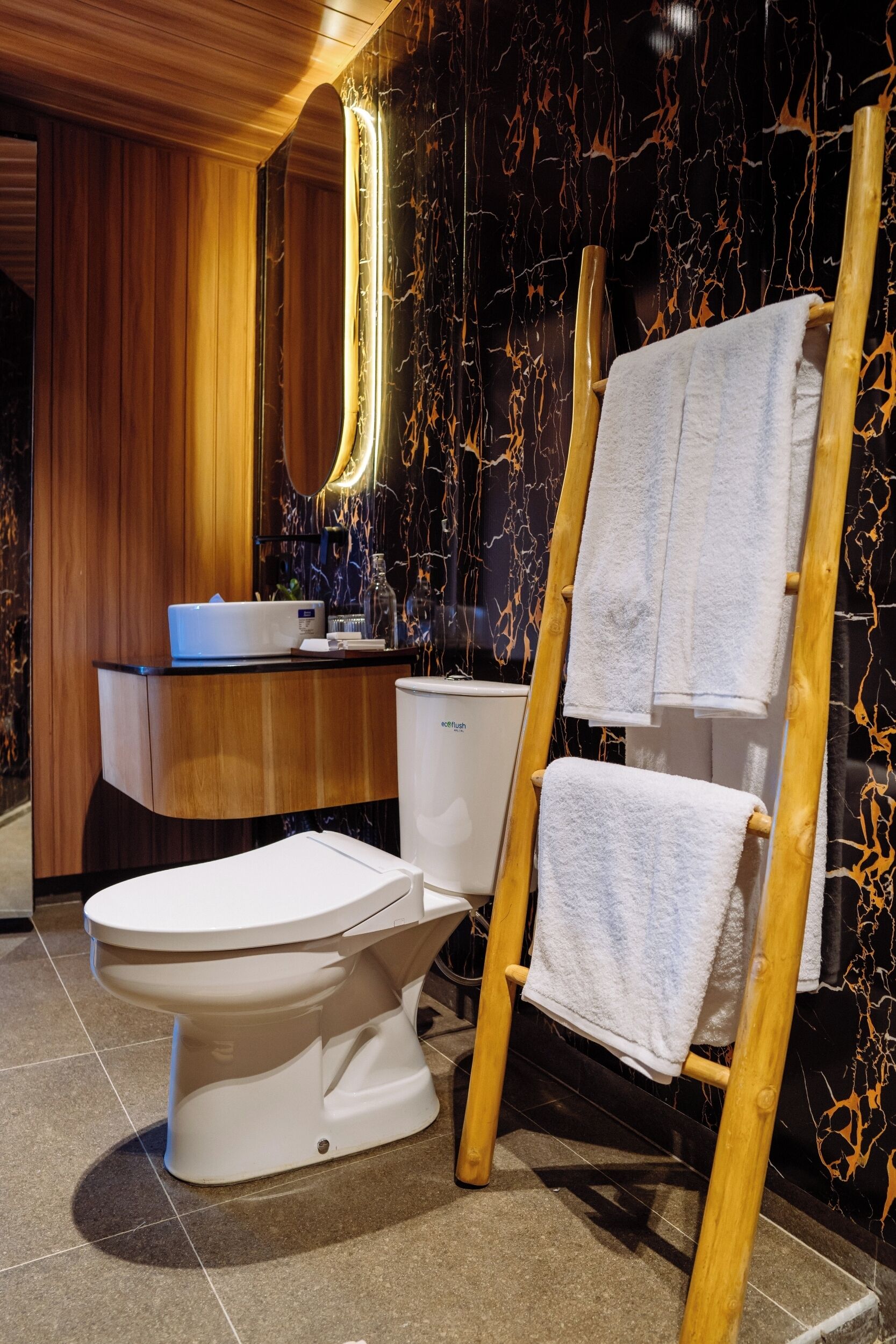 A modern bathroom with a wooden vanity, a toilet, and a towel rack.