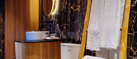 A modern bathroom with a wooden vanity, a toilet, and a towel rack.