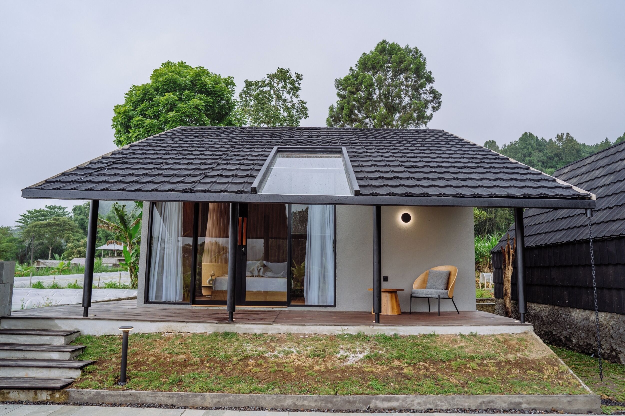 Una casa moderna con techo inclinado, grandes ventanales y una terraza de madera.