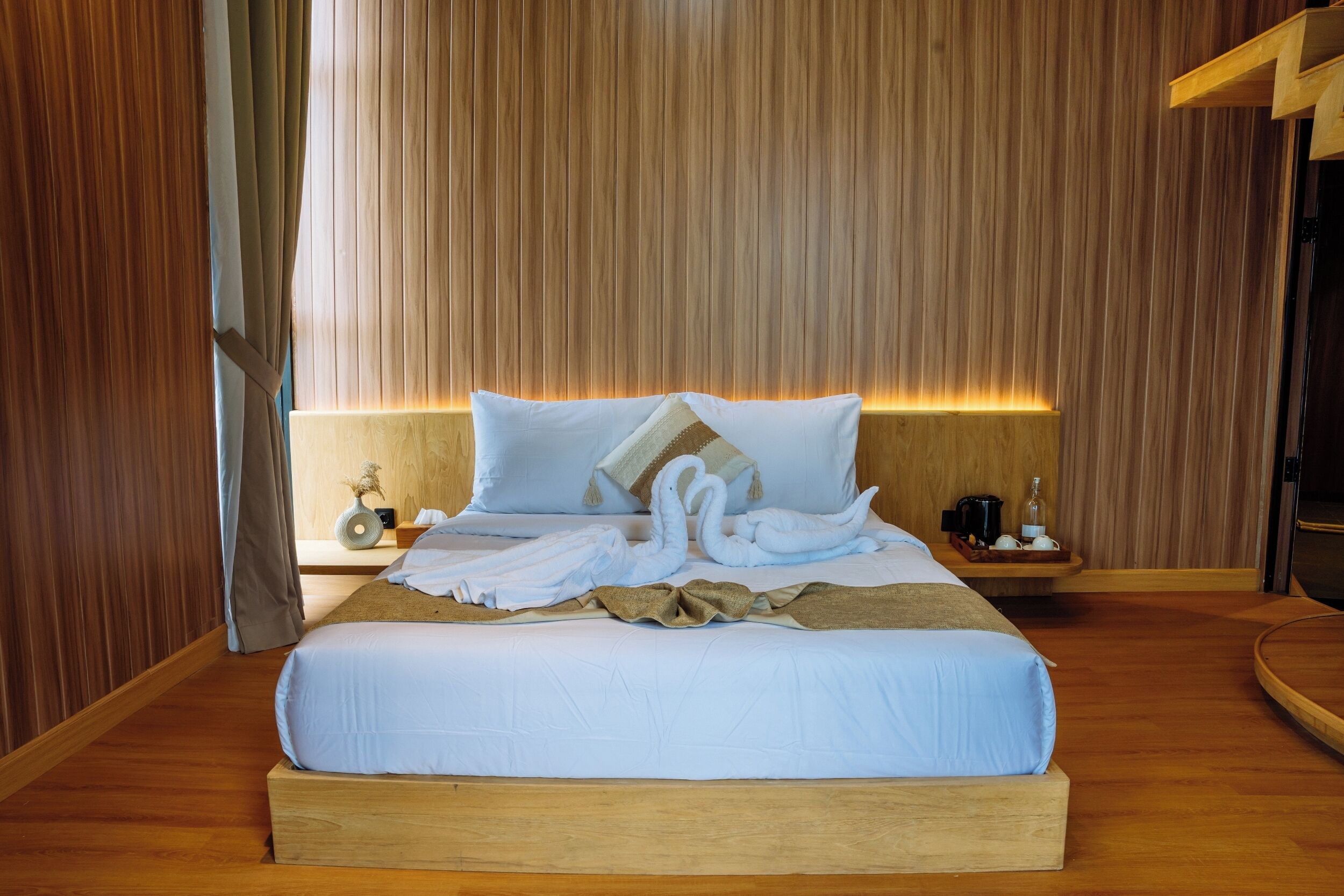 A neatly made bed with white linens and a decorative swan pillow arrangement.