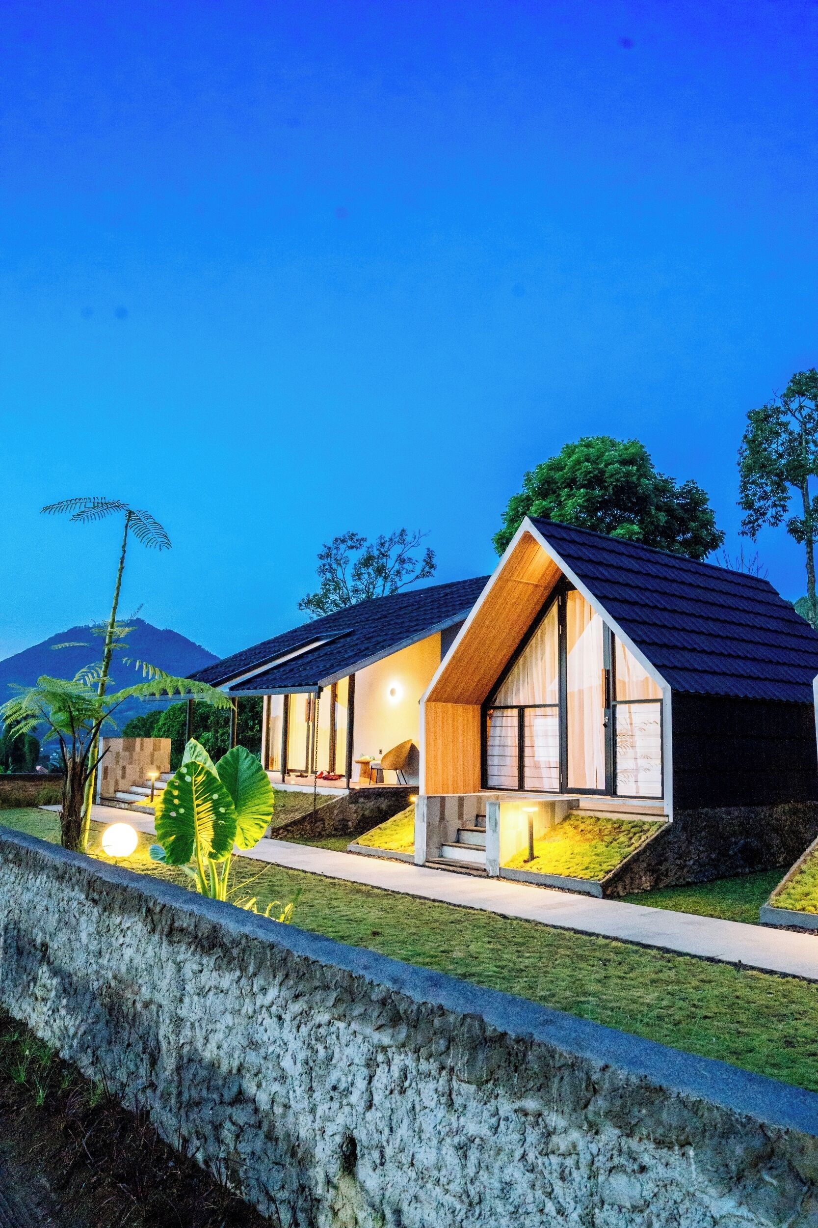 A modern house with a sloped roof, large windows, and a well-lit interior.